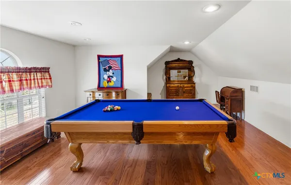 a room with furniture pool table wooden floor and windows