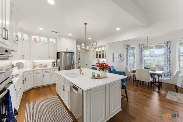 a kitchen that has a lot of cabinets a sink and wooden floor