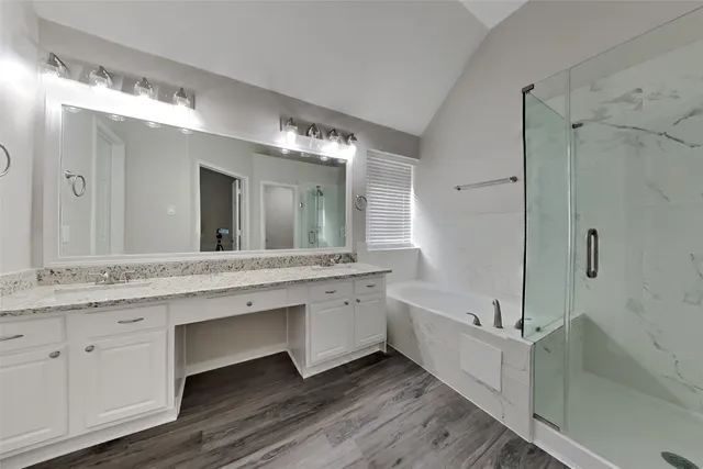 a bathroom with a granite countertop double vanity sink a mirror and a bathtub