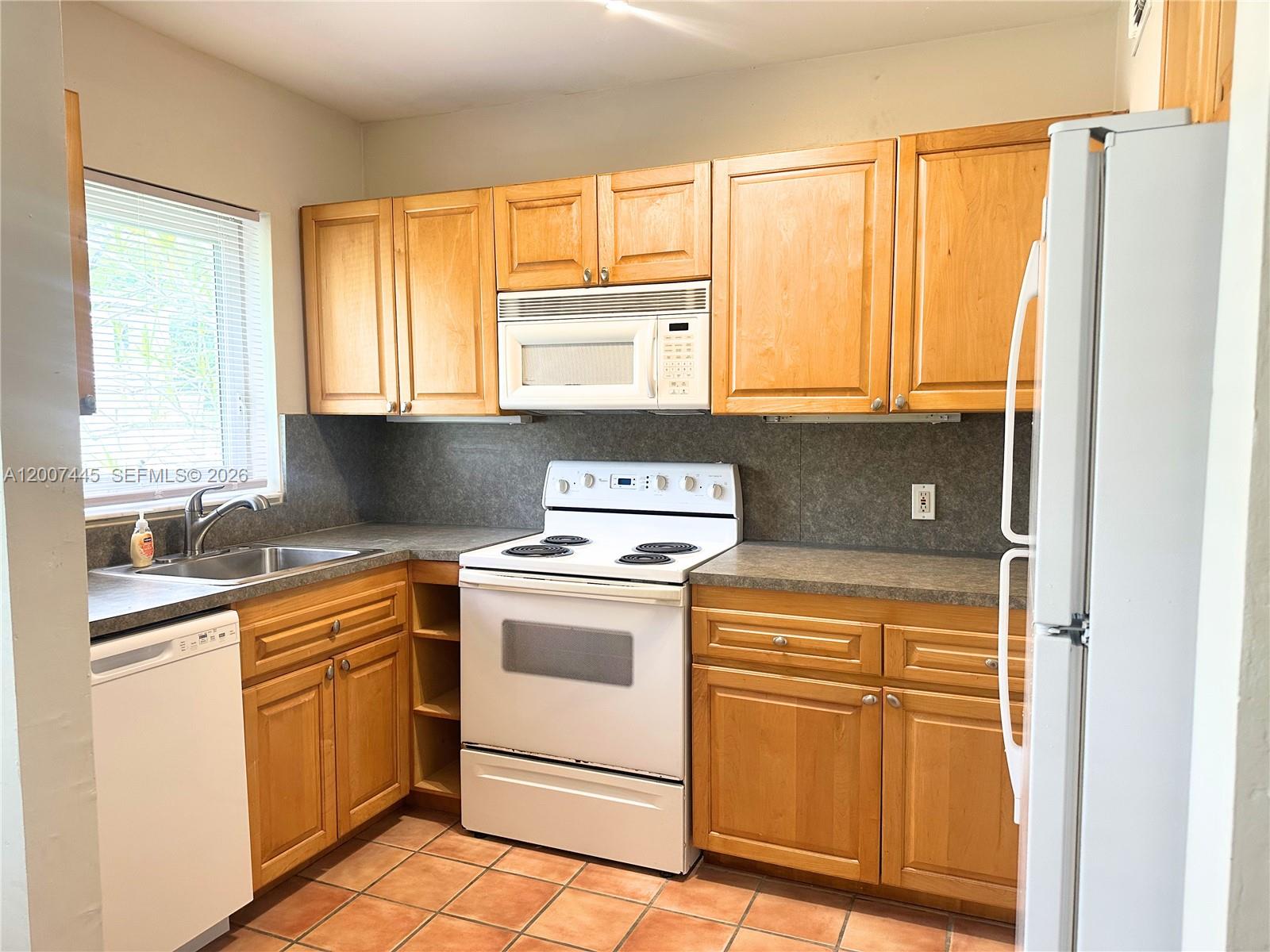 7734 Southwest 55th Avenue, Unit B Miami, FL 33143 - Photo 6 of 11 a kitchen with a white cabinets and white appliances