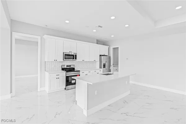 a large white kitchen with stainless steel appliances