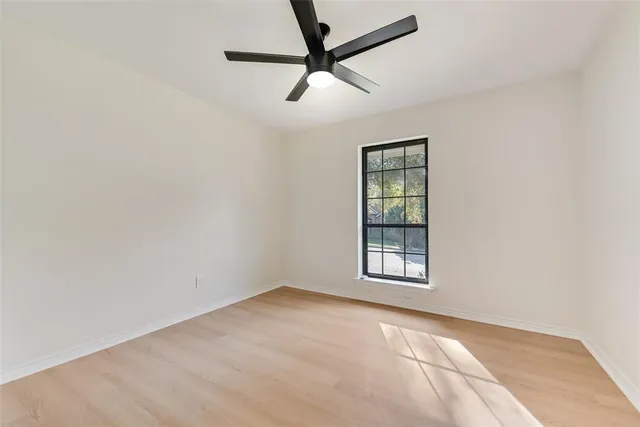 an empty room with a window and a fan