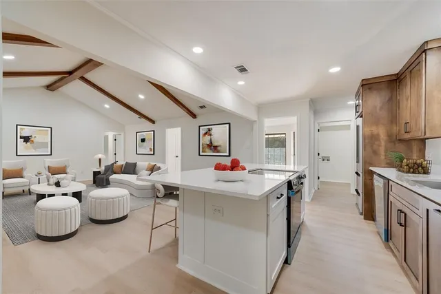 a room with kitchen island a sink and white cabinets