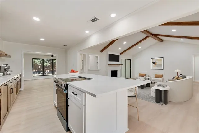 a large white kitchen with stainless steel appliances granite countertop a stove and a refrigerator