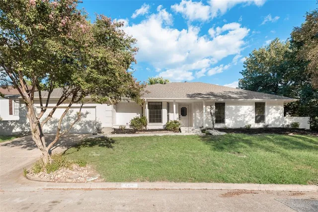 a front view of a house with a garden and trees