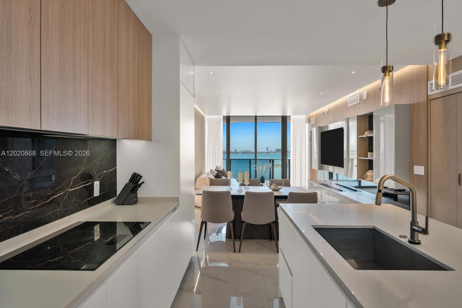 700 Northeast 24th Street, Unit 1602 Miami, FL 33137 - Photo 15 of 30 a kitchen with stainless steel appliances a sink dishwasher a stove a microwave oven and white cabinets with wooden floor