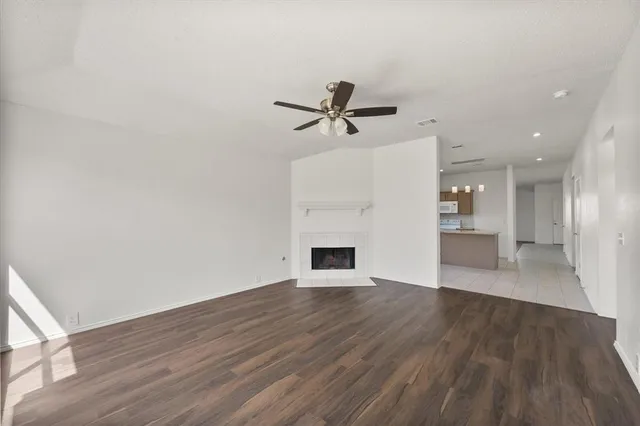 a view of an empty room with wooden floor and a fireplace