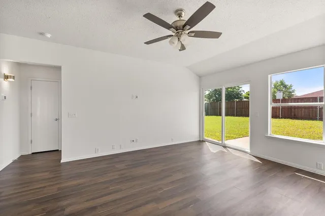 a view of a livingroom with a fireplace a ceiling fan and wooden floor