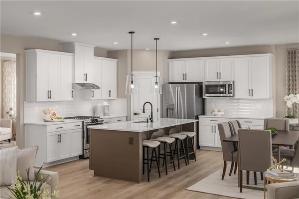 a kitchen with stainless steel appliances granite countertop a table chairs sink refrigerator and cabinets