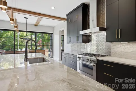 a large white kitchen with a stove and a large window