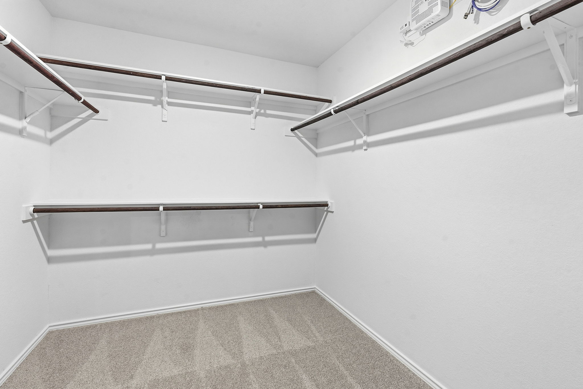 164 Cinnabar Lane, Unit 2 Kyle, TX 78640 - Photo 12 of 21 Spacious walk-in closet featuring light gray patterned carpet, multiple dark wood-finish hanging rods, and white wall shelving
