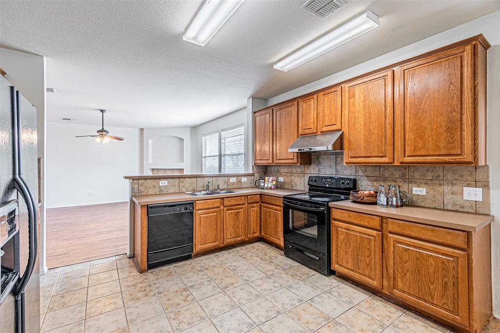 7804 Hidden Path Lane Denton, TX 76210 - Photo 12 of 40 a kitchen with stainless steel appliances granite countertop a stove top oven a sink dishwasher and a refrigerator