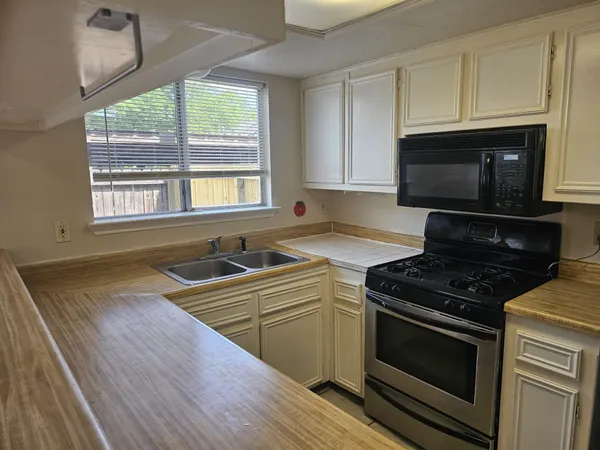 a kitchen with granite countertop a stove a sink and a microwave