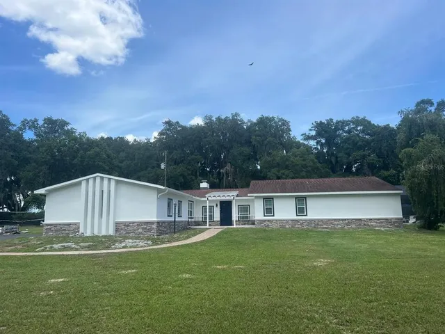 a front view of house with yard and trees in the background