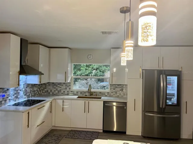 a kitchen with stainless steel appliances kitchen island granite countertop a table chairs and a refrigerator