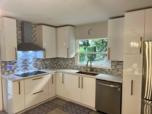 a kitchen with stainless steel appliances granite countertop a sink a stove and a wooden floors