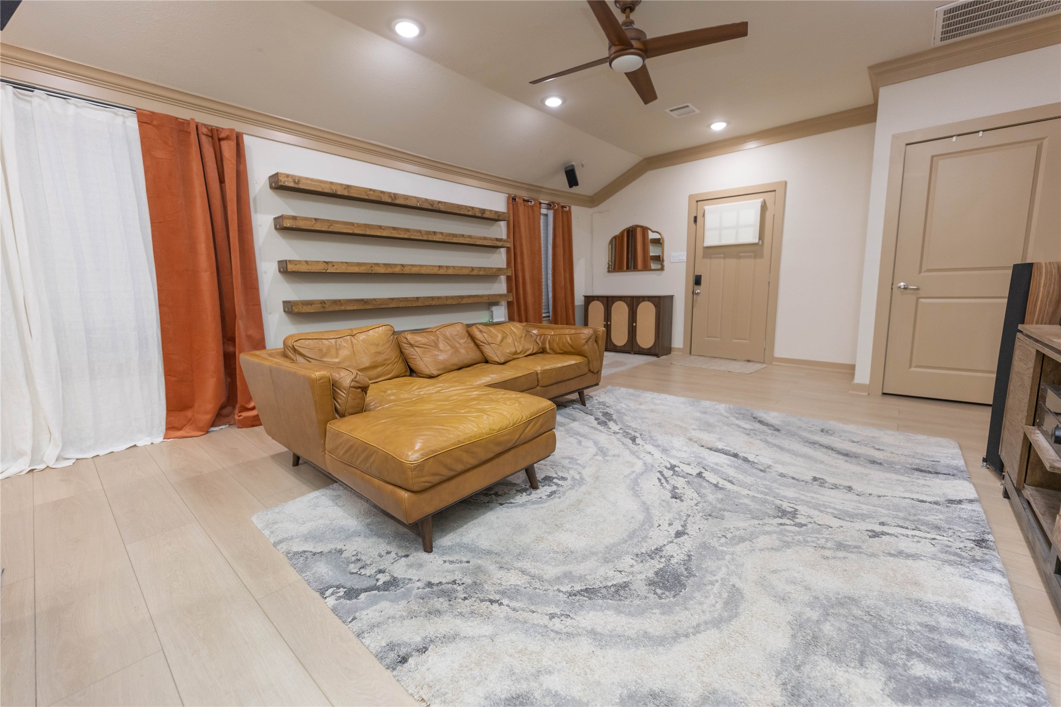 8007 Capitol Street Houston, TX 77012 - Photo 9 of 25 This spacious living room features a modern floating and stylish shelves. The room is bright with natural light, enhanced by warm wood accents and ceiling fan, creating a welcoming atmosphere.