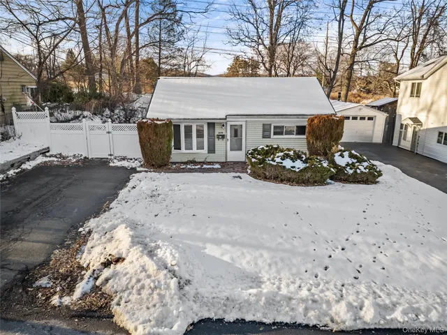 a view of a white house with a yard covered with snow in the backyard