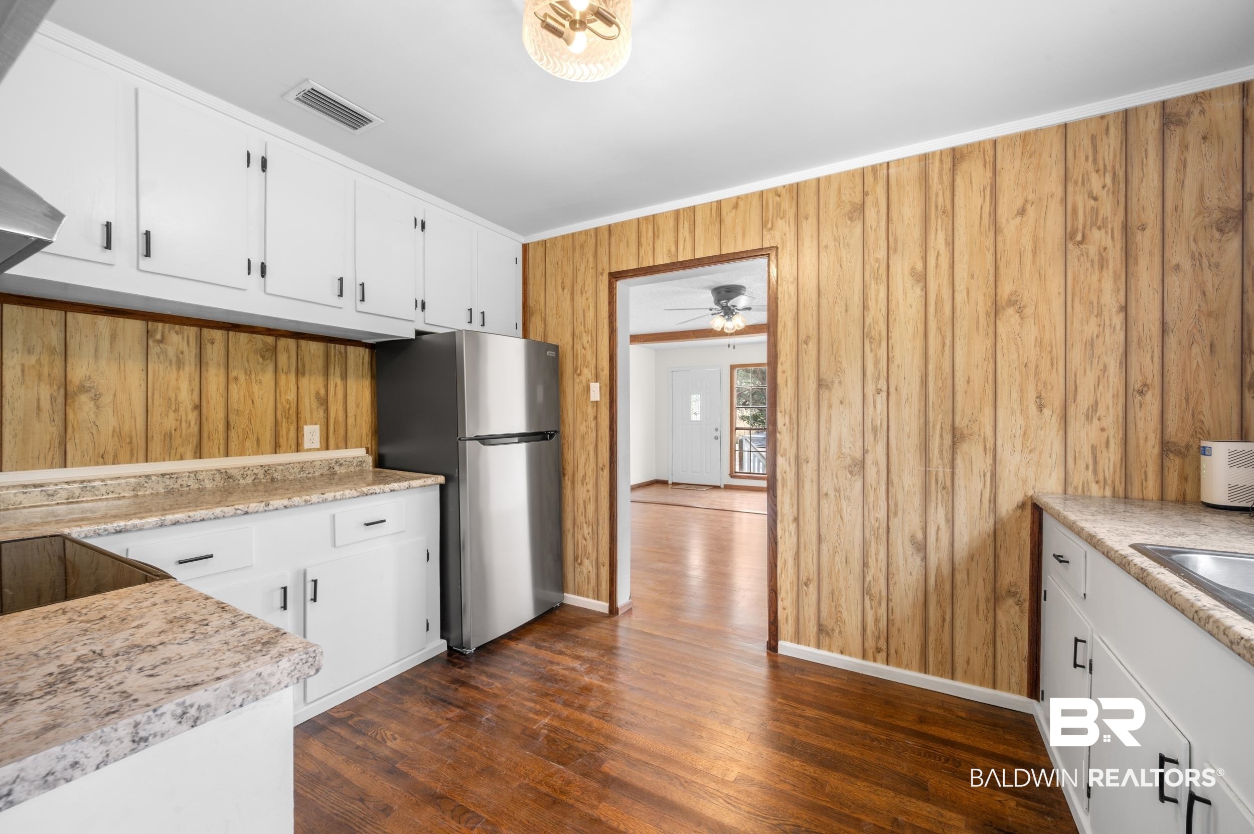 35780 Spring Road North Stapleton, AL 36578 - Photo 15 of 41 Kitchen with white cabinetry, freestanding refrigerator, dark wood finished floors, wood walls, and ornamental molding