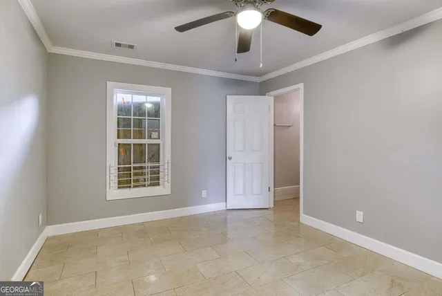 an empty room with chandelier fan and windows