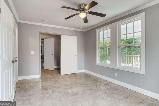 an empty room with chandelier fan and windows
