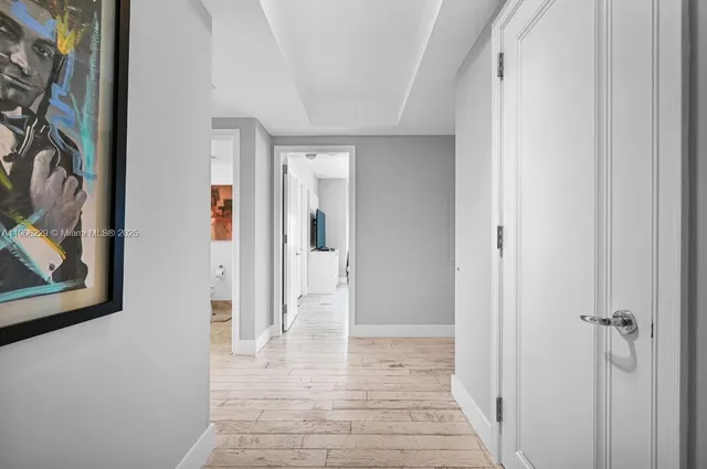 a view of a hallway with wooden floor and a bathroom