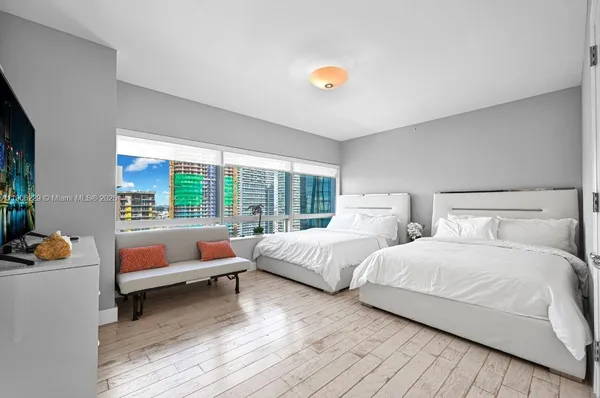 a bedroom with two beds and a couch next to a window