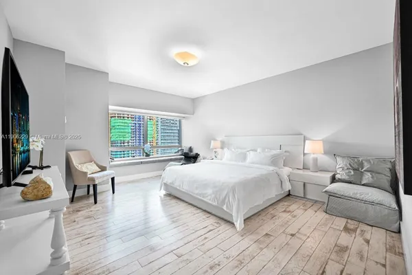 a spacious bedroom with a bed and wooden floor