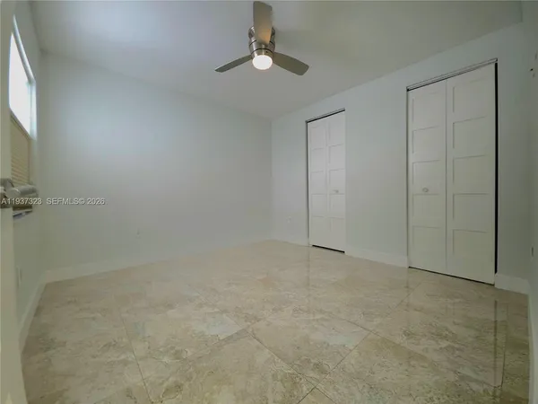 a view of an empty room with a chandelier fan