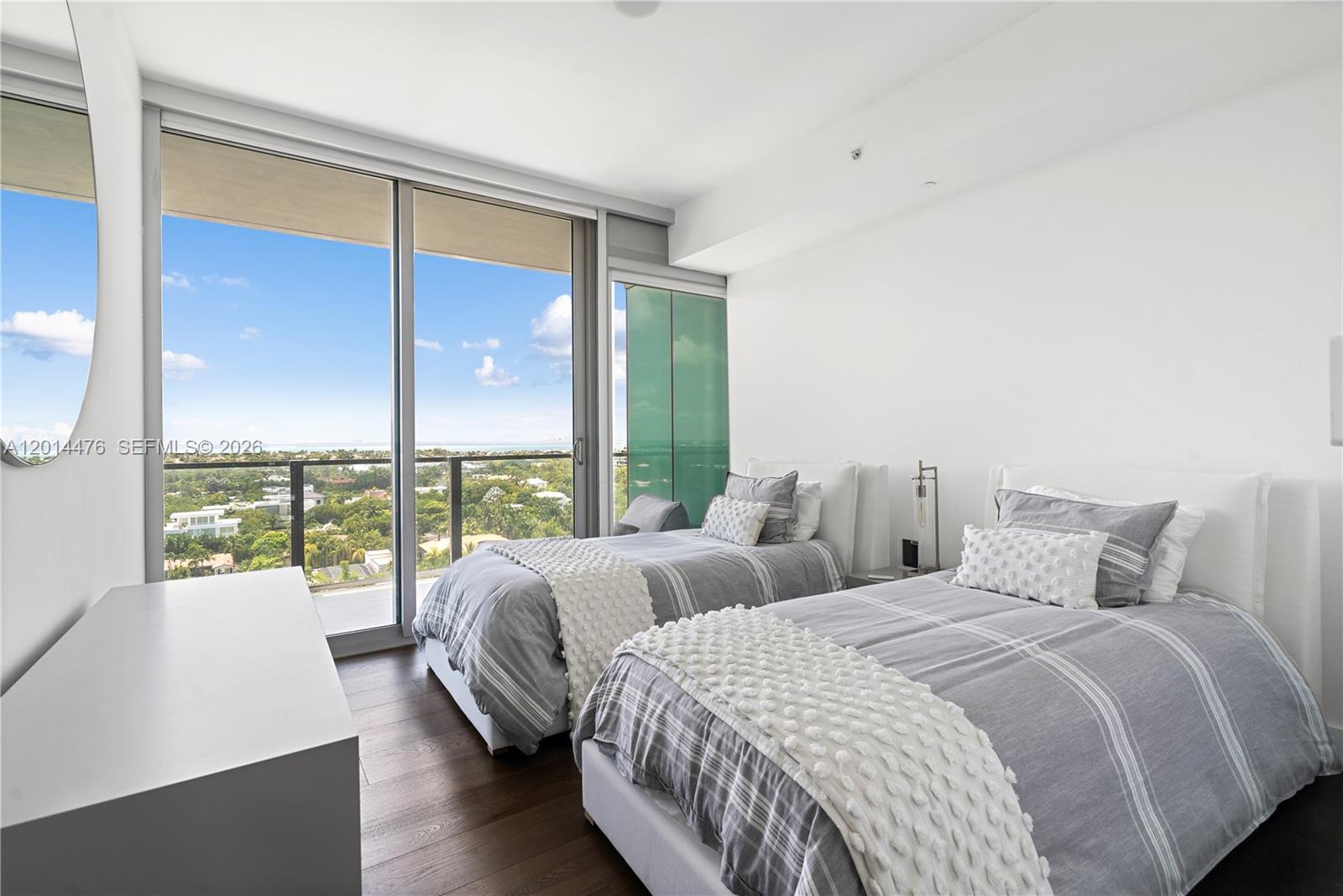 360 Ocean Drive, Unit 1106S Key Biscayne, FL 33149 - Photo 14 of 67 Guest Bedroom – This bright bedroom features two beds, wide-plank wood flooring, and floor-to-ceiling glass doors opening to the balcony. Elevated views and abundant natural light make the room feel airy and inviting.