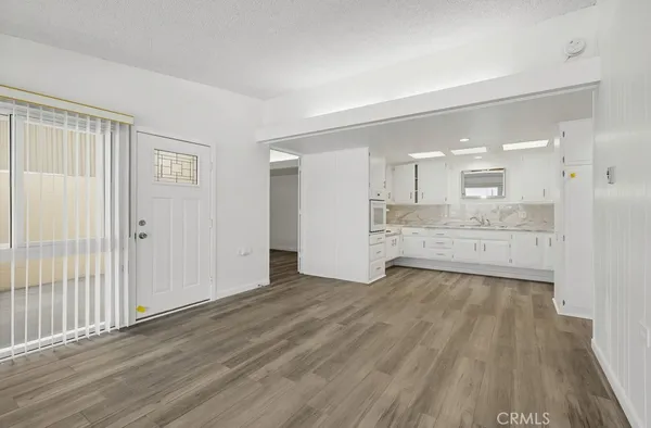 a kitchen with white cabinets sink and dishwasher with wooden floor
