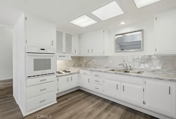 a kitchen with stainless steel appliances granite countertop a sink and cabinets with wooden floor