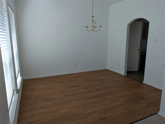 a view of empty room with wooden floor and window