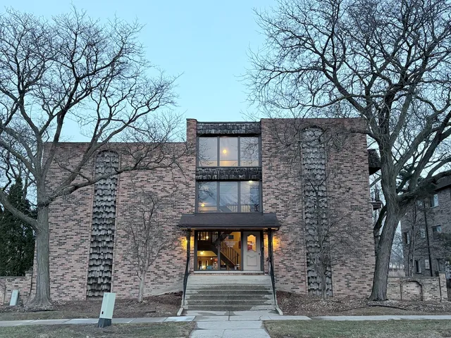 front view of a brick building with large trees