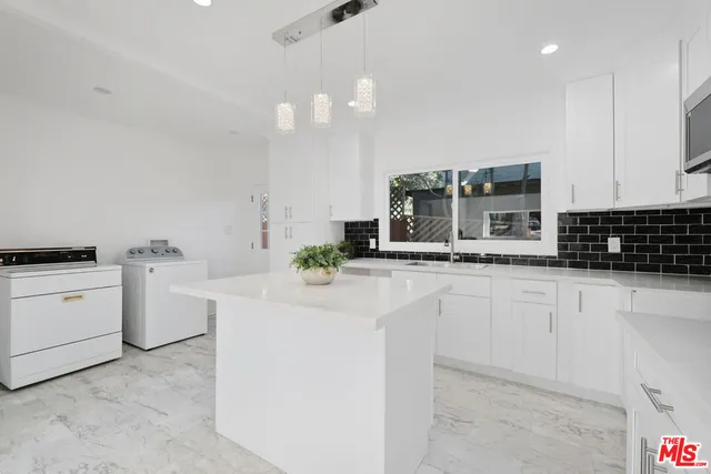 a kitchen with white cabinets and sink