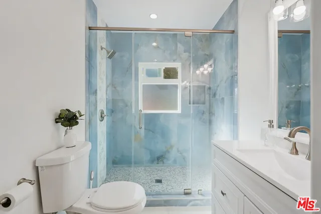 a bathroom with a shower sink vanity mirror and toilet