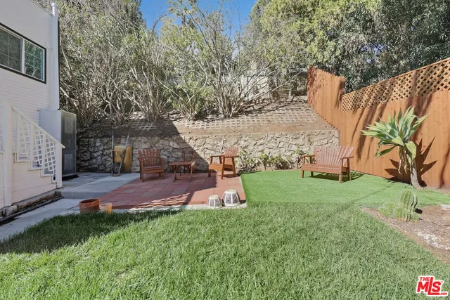 a view of a yard with plants and a bench