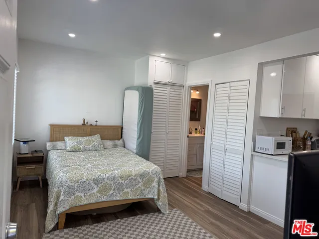 a bedroom with a bed and a refrigerator