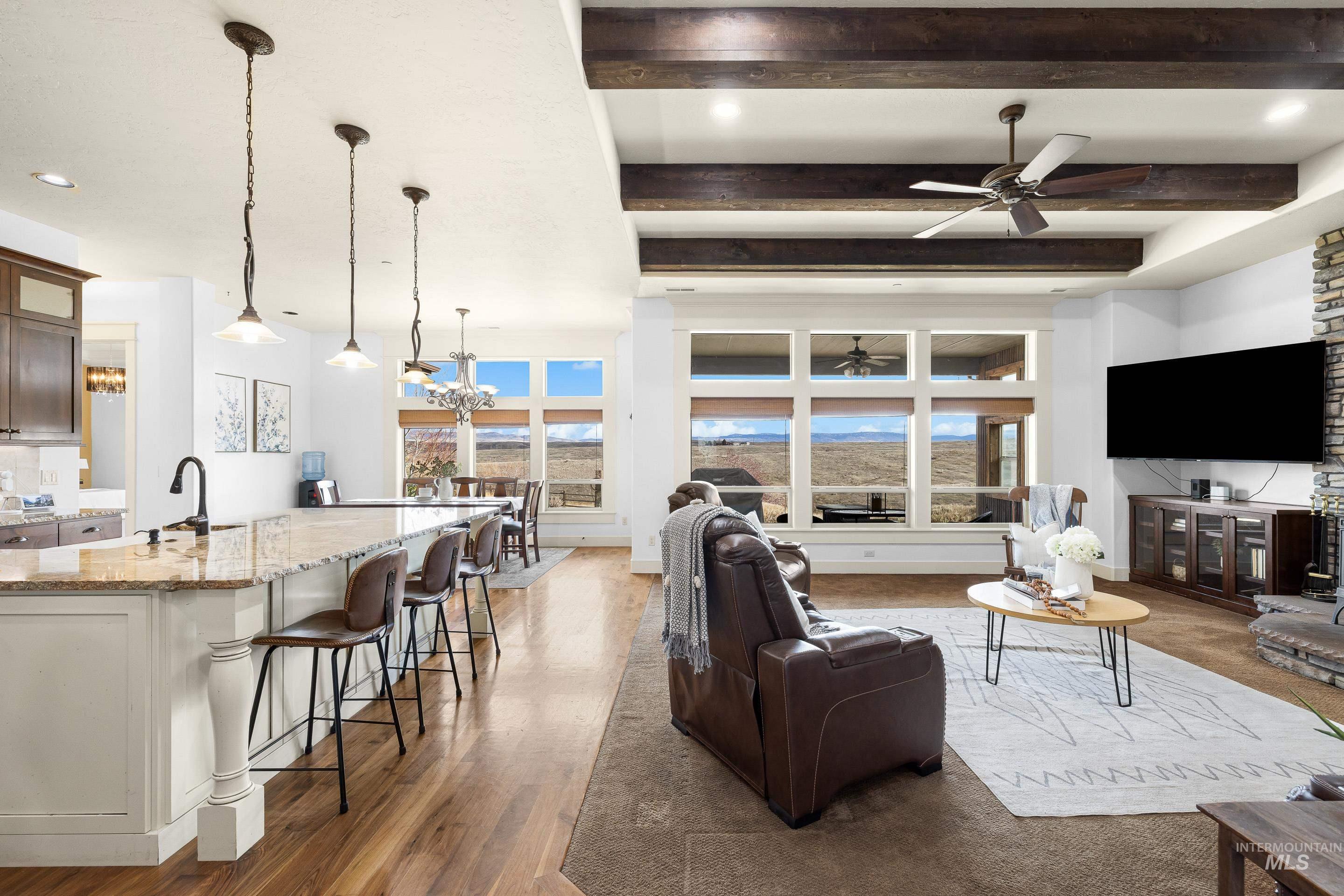 7521 North Grand Ridge Lane Eagle, ID 83616 - Photo 15 of 50 Living room featuring beamed ceiling, light wood-type flooring, a ceiling fan, and hanging lights