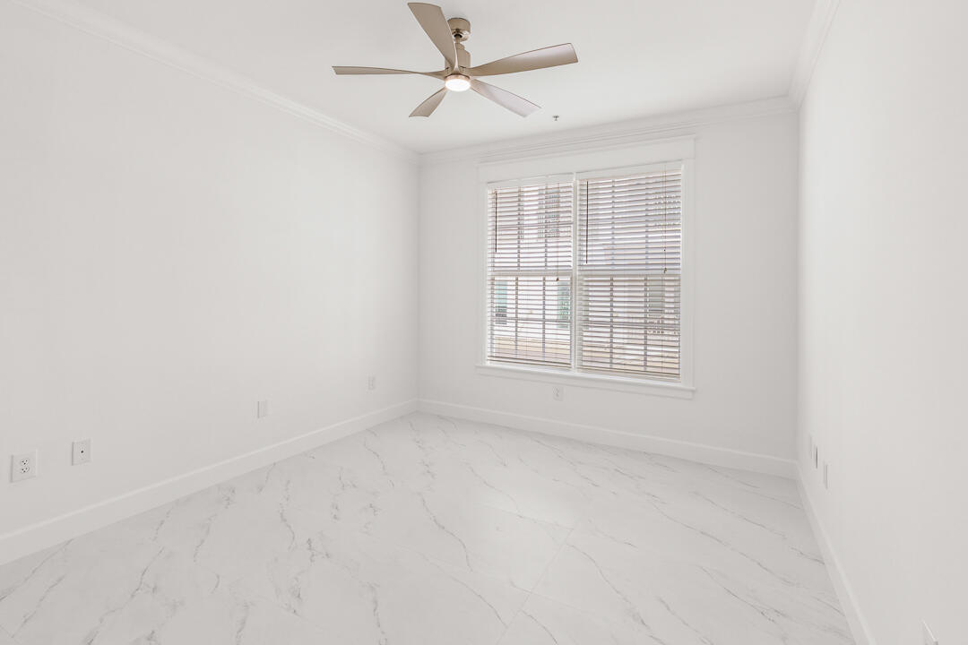47 Southwest Osceola Street, Unit 206 Stuart, FL 34994 - Photo 21 of 47 an empty room with chandelier fan and windows