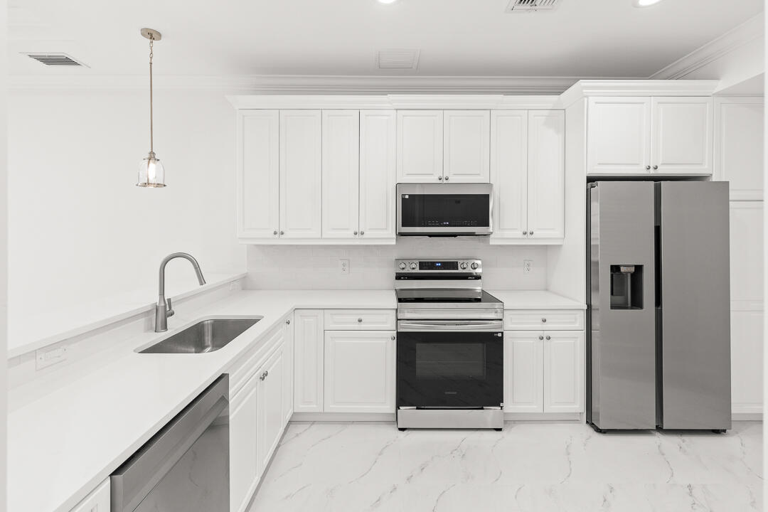 47 Southwest Osceola Street, Unit 206 Stuart, FL 34994 - Photo 5 of 47 a kitchen with stainless steel appliances a refrigerator sink and white cabinets