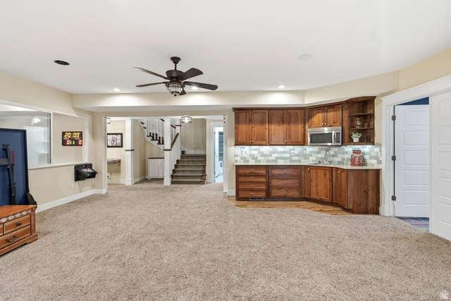 672 Perry Hollow Drive Mapleton, UT 84664 - Photo 74 of 106 Spacious carpeted room featuring a built-in wet bar with wood cabinetry, stainless steel microwave, and tile backsplash