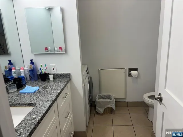 a bathroom with a granite countertop sink a toilet and a mirror
