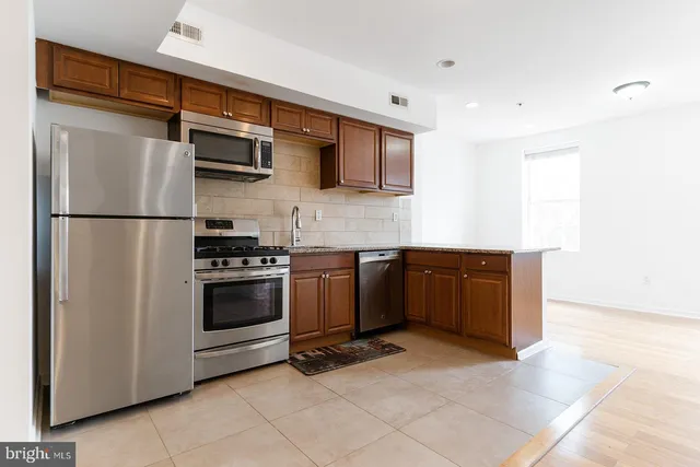 a kitchen with stainless steel appliances granite countertop a refrigerator and a stove