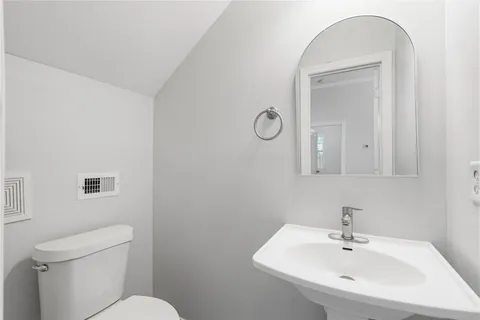 a bathroom with a toilet a sink and mirror