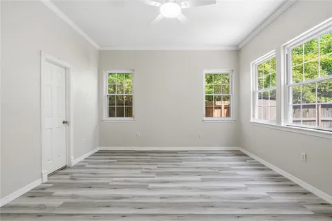 a view of an empty room with wooden floor and a window