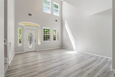 a view of an empty room with window and wooden floor
