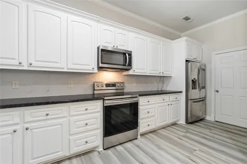 a kitchen with granite countertop white cabinets stainless steel appliances and sink