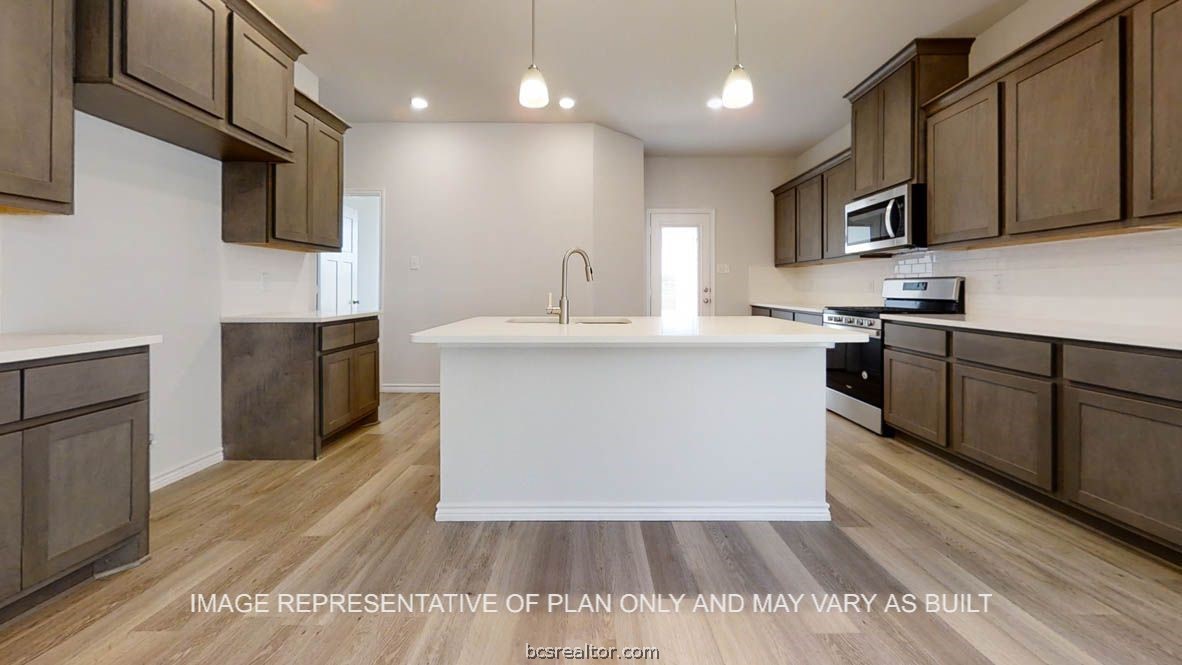 a kitchen with stainless steel appliances granite countertop a sink a stove top oven a refrigerator with wooden floors