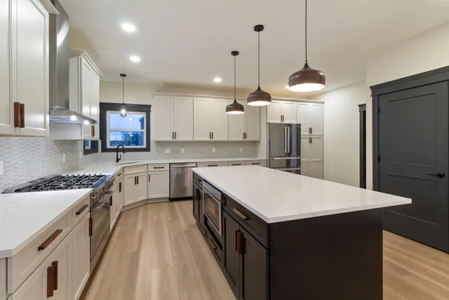 a kitchen with a stove a refrigerator a sink and chairs